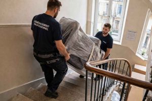 Déménageurs professionnels transportant des meubles dans un escalier. Illustration du recours à une entreprise spécialisée
