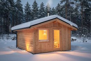 Chalet sauna en bois au cœur d'un jardin enneigé, lumière chaleureuse visible depuis l'intérieur. Ambiance scandinave authentique pour un sauna extérieur en hiver